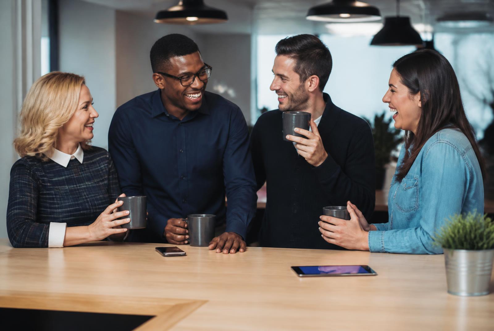 Brand Starting team members collaborating over laptops and coffee in the studio